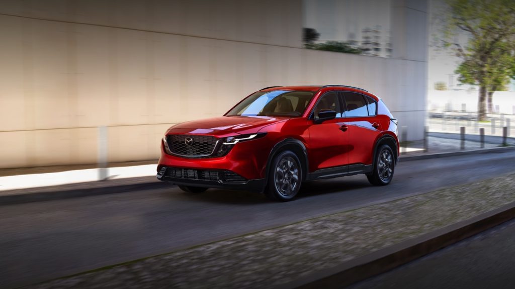 2026 Mazda CX-5 driving on a city street near a modern building