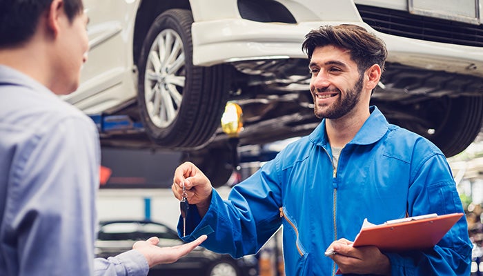 Service technician giving keys back to customer after service of vehicle at Mazda 112 in Medford NY
